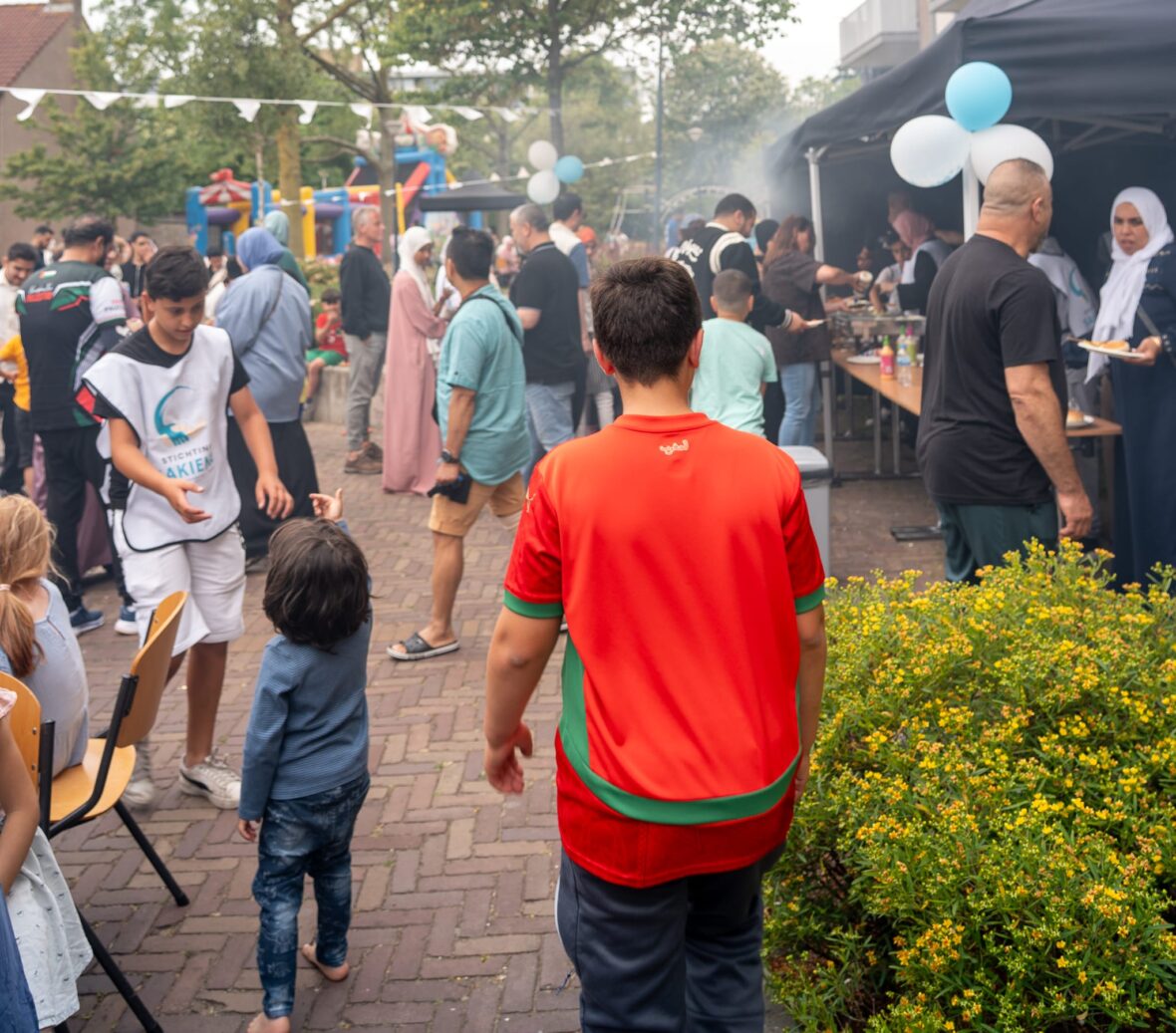 Druk bezochte buitenactiviteit van Stichting Sakiena met kraampjes, ballonnen en bezoekers van alle leeftijden