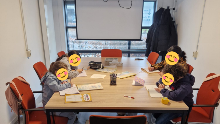 Kinderen maken hun huiswerk aan tafel tijdens de bijles van Stichting Sakiena in Voorschoten