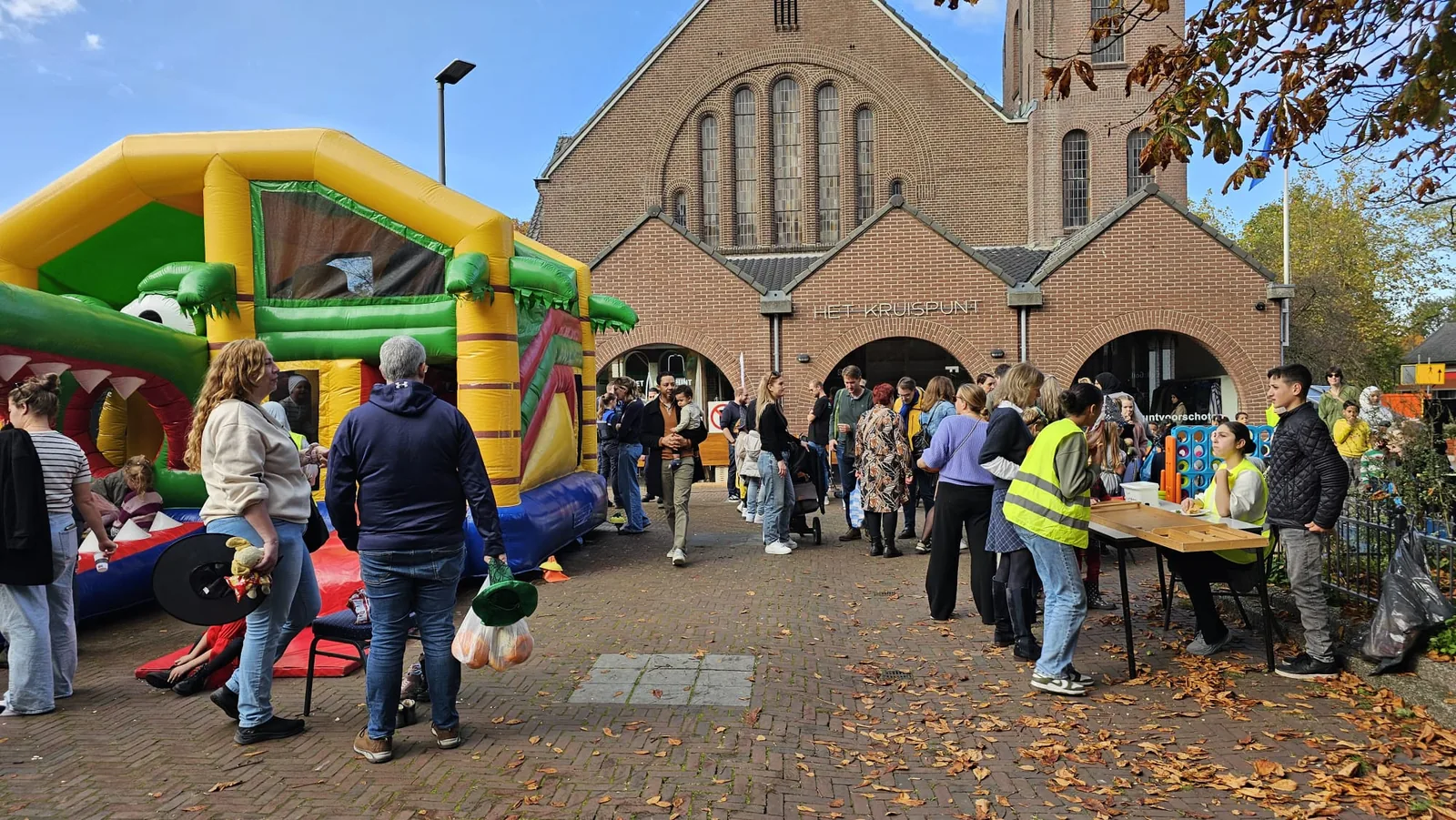 Overzicht van het evenement Culturen in de Wijk, met springkussen en bezoekers voor het gebouw