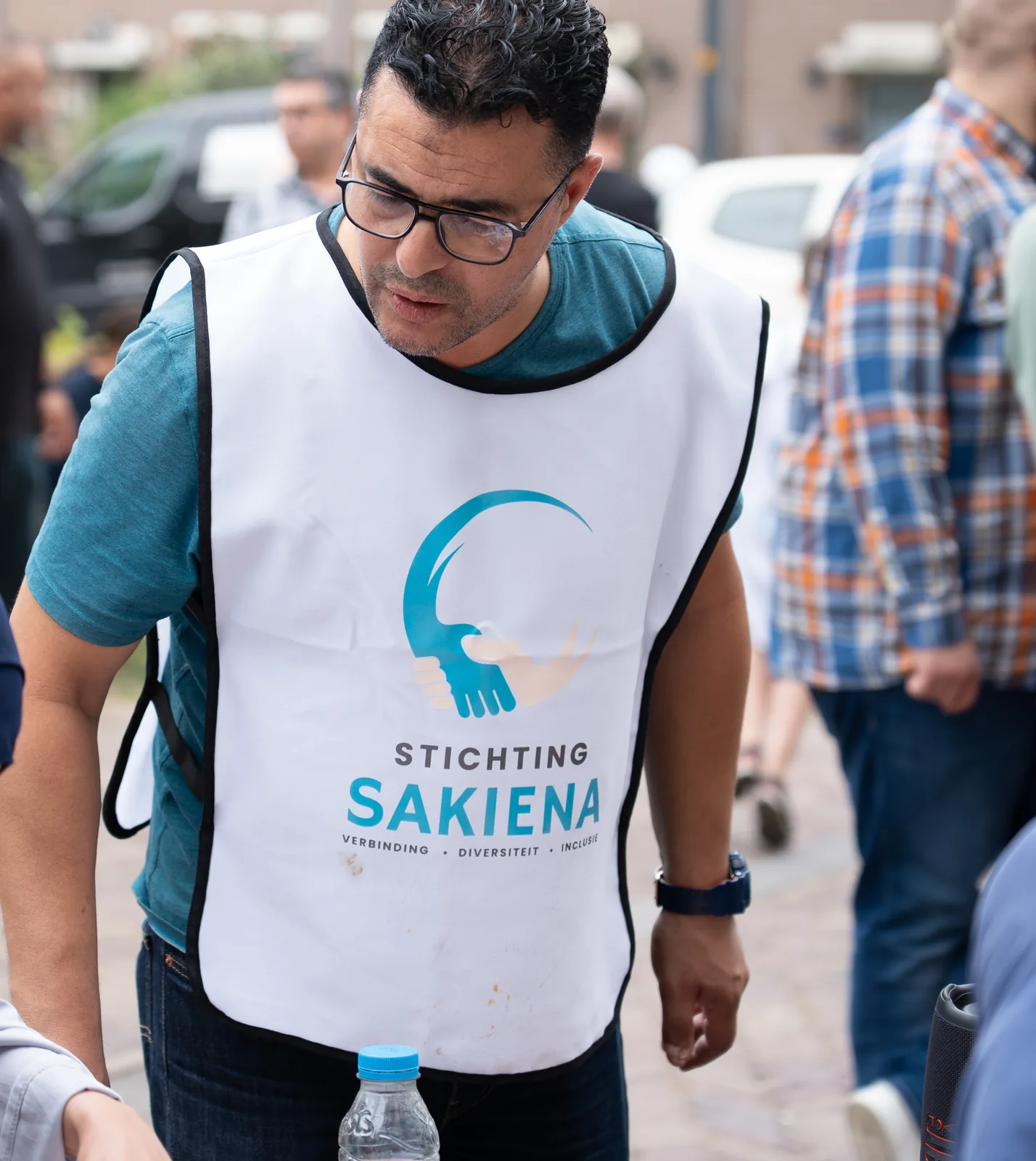 Portret van een vrijwilliger met het Sakiena-hesje tijdens het buurtfeest