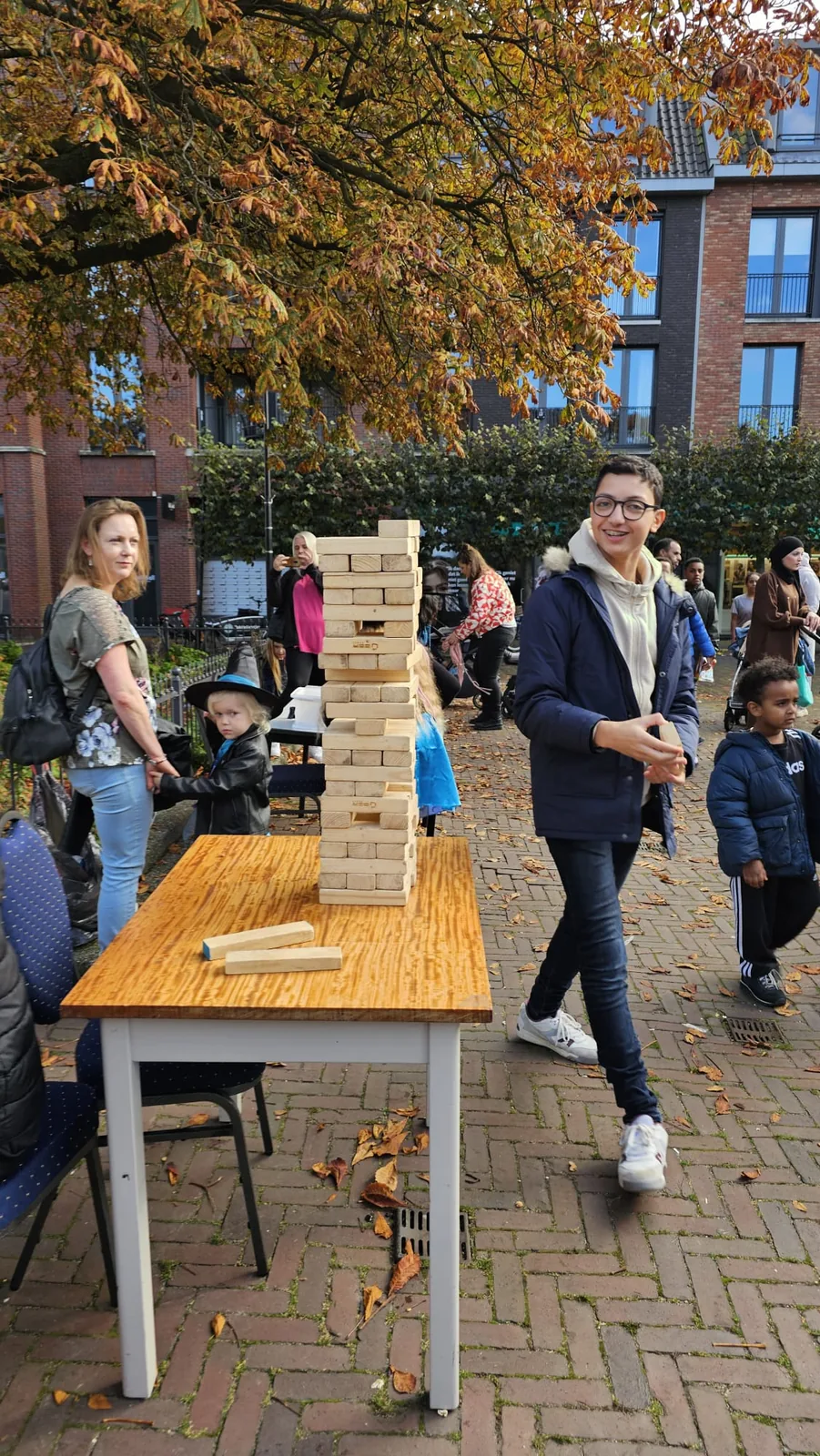 Bezoekers spelen reuzejenga aan een tafel buiten tijdens Culturen in de Wijk