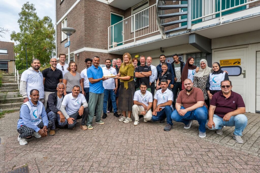 Groep deelnemers en medewerkers van Stichting Sakiena en De Sleutels met een taart bij de start van het project in Leiden