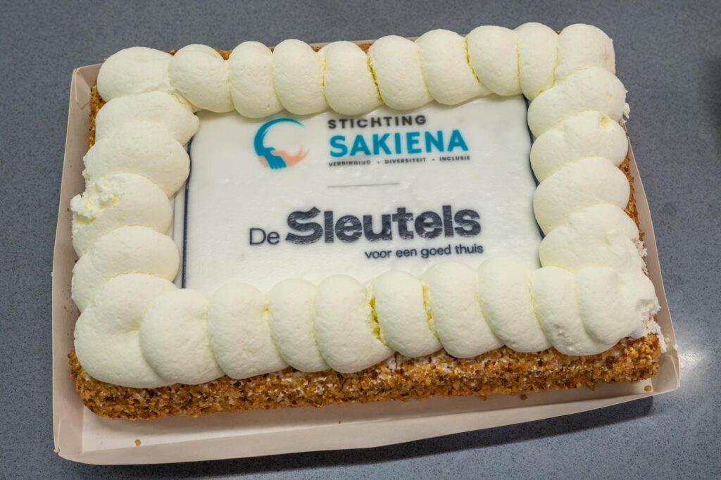 Taart met daarop de logo's van Stichting Sakiena en woningbouwvereniging De Sleutels