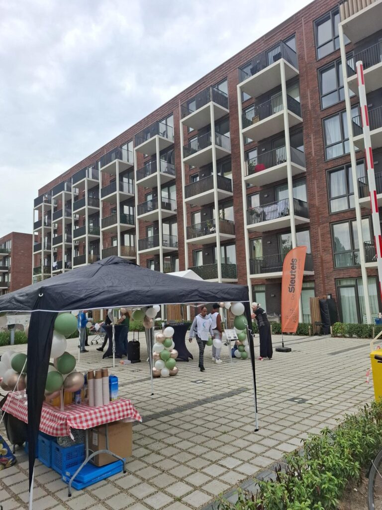 Het nieuwe appartementengebouw van De Sleutels aan de Willem de Zwijgerlaan, met partytenten, ballonnen en een vlag van De Sleutels op het plein ervoor