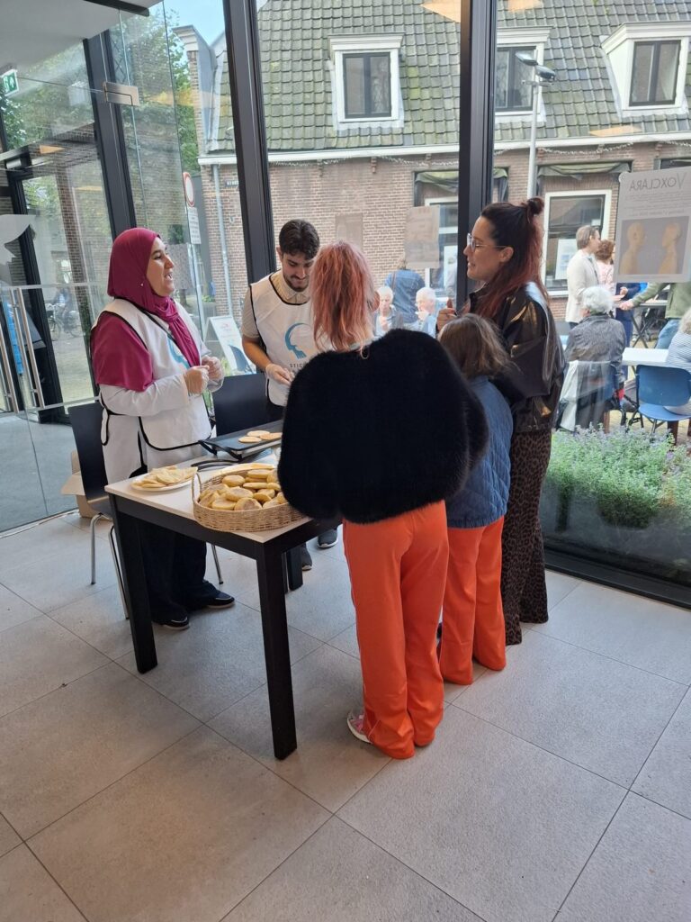 Vrijwilliger deelt broodjes uit aan bezoekers bij de ingang