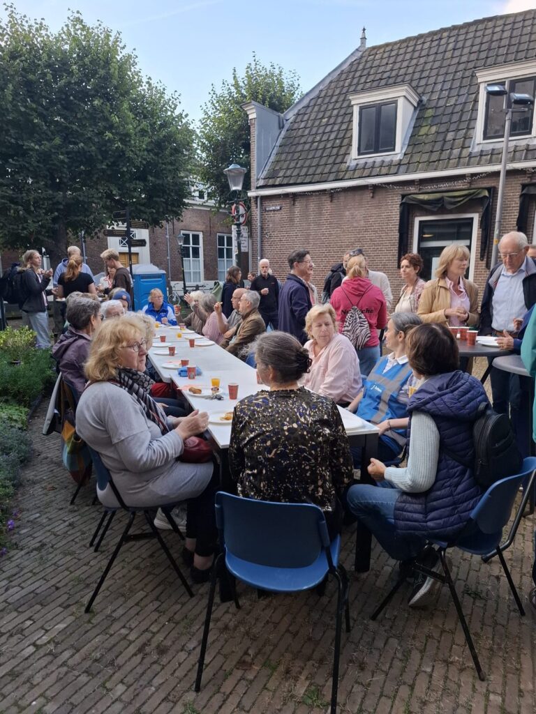 Bezoekers zitten aan lange tafels op de binnenplaats en praten met elkaar